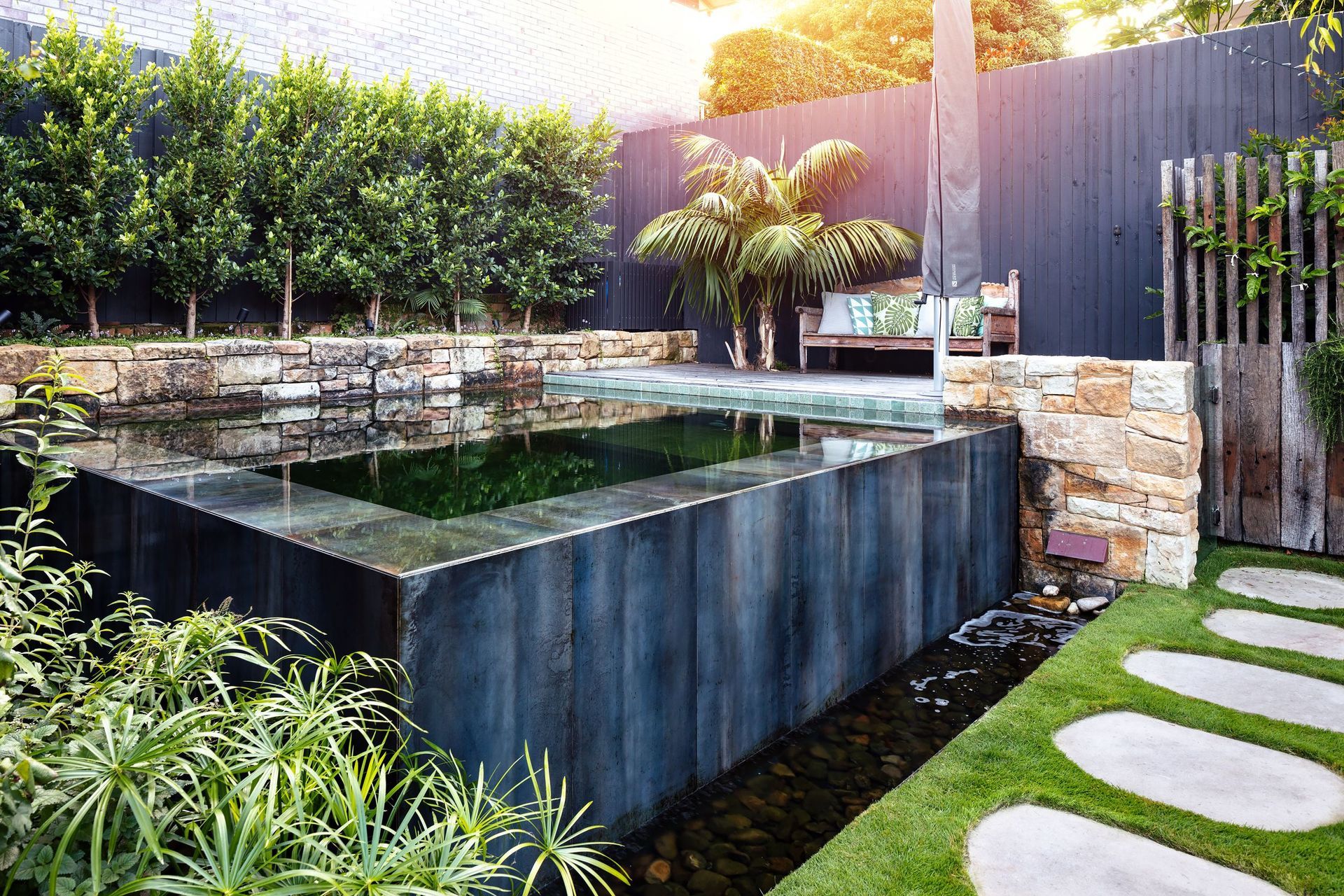 A square natural pool extruded from the ground in lush surroundings by Land Forms. | Photography: Luc Remond