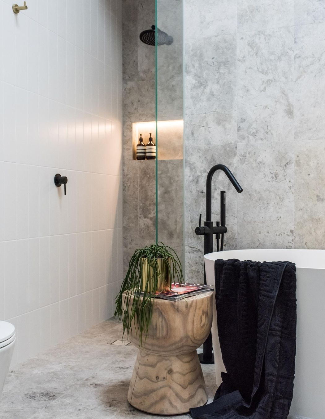 A cosy walk-in shower, featuring the bold Round Wall Shower Arm in Matte Black from Meir.