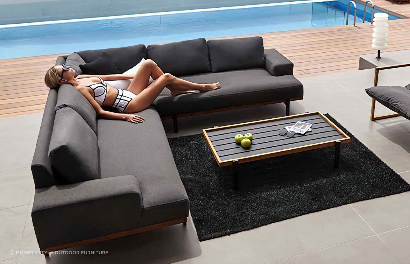 Woman-lounges-on-a-modern-dark-grey-l-shaped-outdoor-sofa-2.jpg