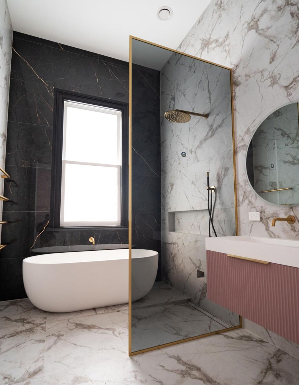 With a soft tint and gold frame, this glass shower screen is sleek and elegant.