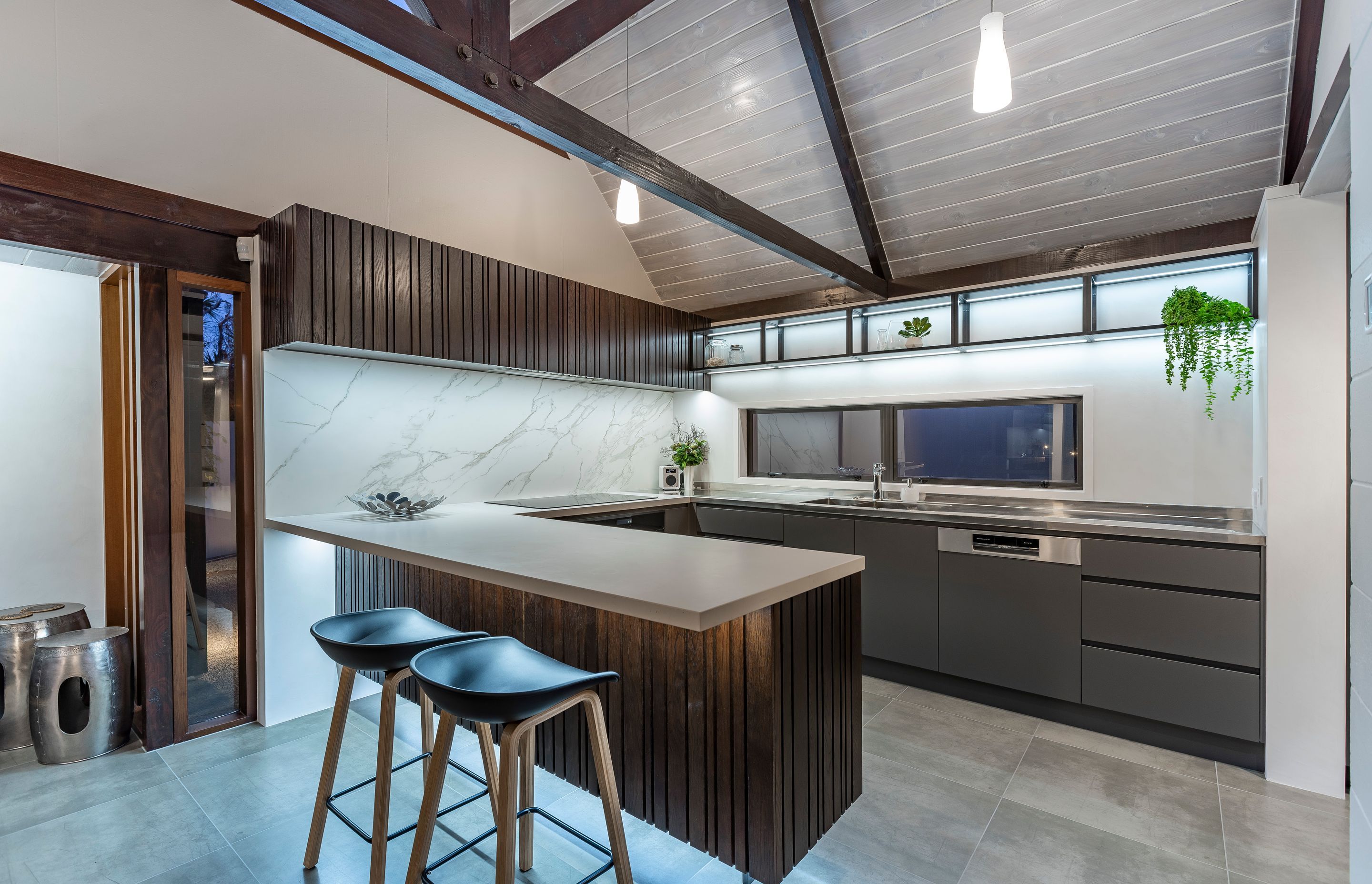 The under-lit, cantilevered peninsula appears to float above the kitchen floor helping the structure appear lightweight and unobtrusive within the larger space.