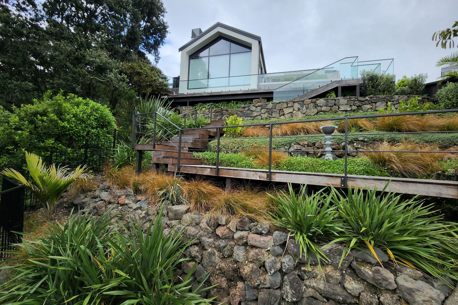The steep site called for hardwood stairs to a deck surrounded by clusters of native shrubs.