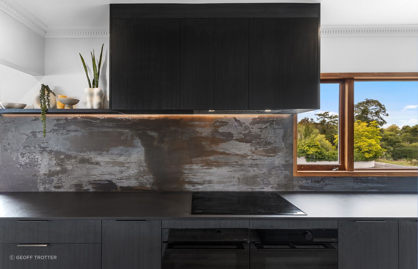 The completed kitchen features dark elements like the Dekton Trilium splashback — chosen for its oxidised finish that mimics the look of reclaimed metal.
