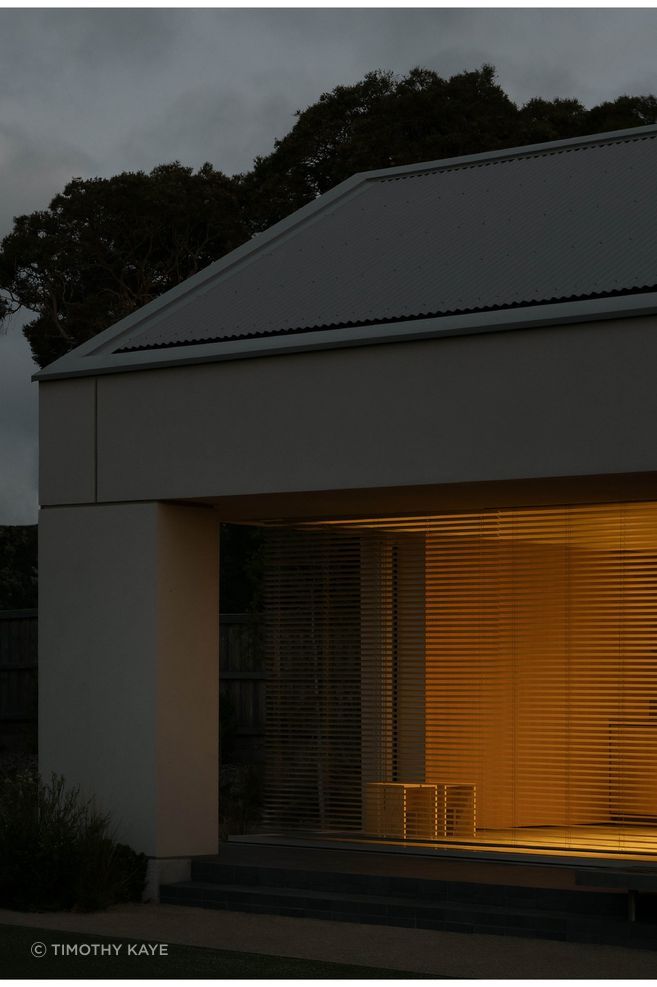 At Sorrento Bathhouse, a deeply recessed opening frames the softly lit interior, allowing the simple exterior form to hold its composure after dark.
