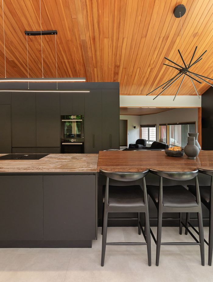 The variation in benchtop materials adds contrast and texture, visually dividing the dining area from the kitchen work zone.