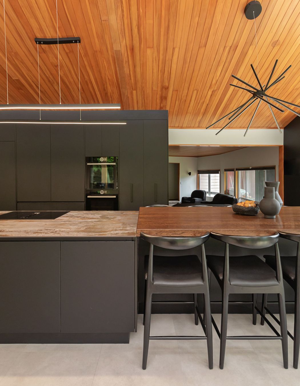 The variation in benchtop materials adds contrast and texture, visually dividing the dining area from the kitchen work zone.