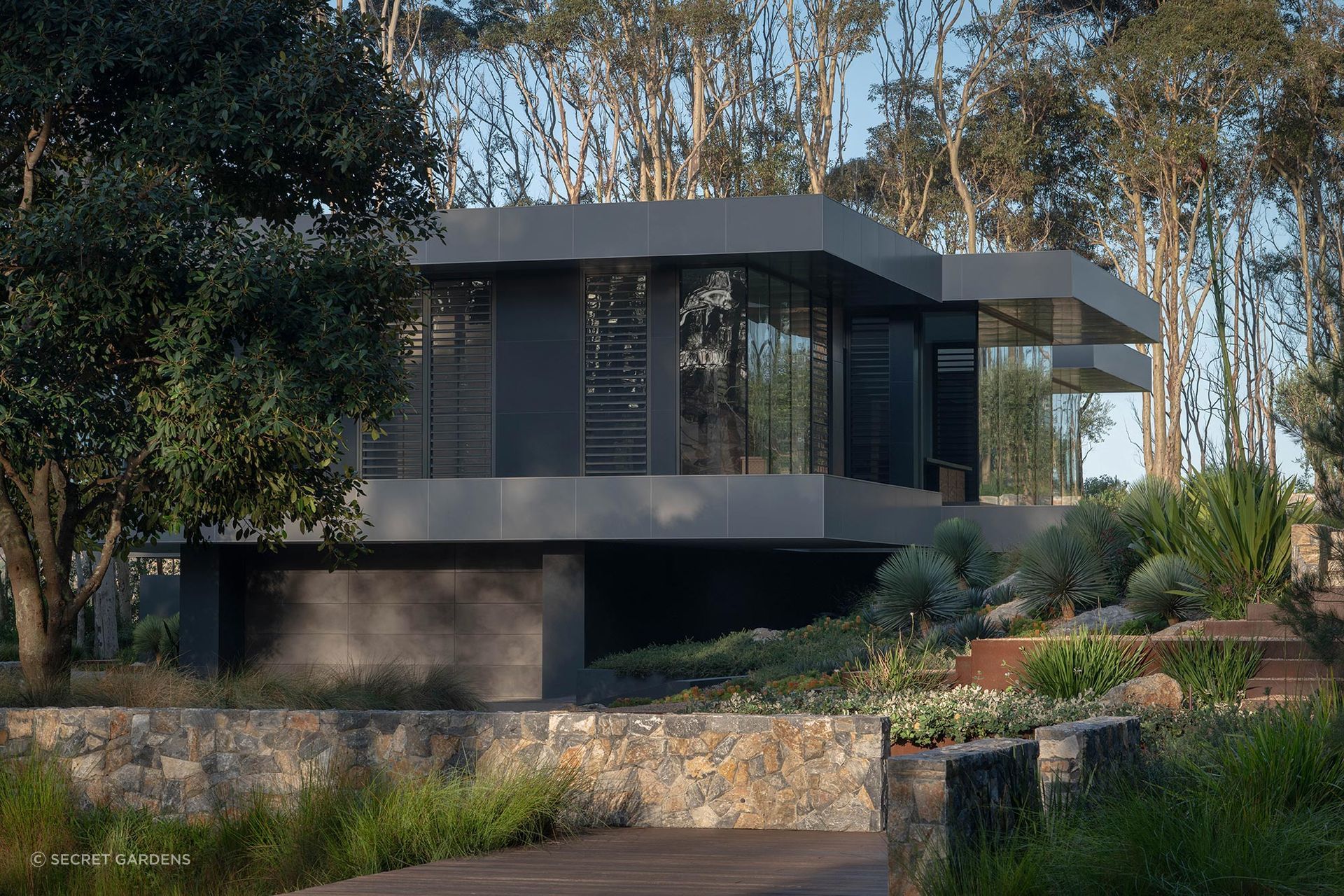 At Bracken, low-key planting, stone walling and Corten steel details mediate between the home’s contemporary architecture and the mature Spotted Gums surrounding it.
