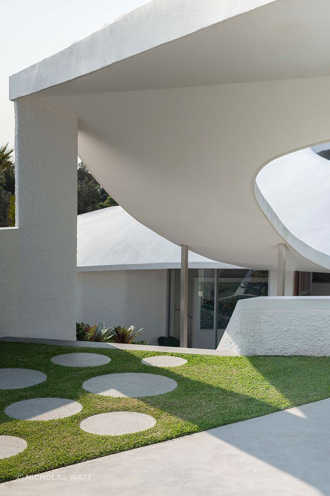 Circular stepping stones and curved garden walls carry the geometry of Cove House through the landscape, creating a clear connection between architecture and garden.