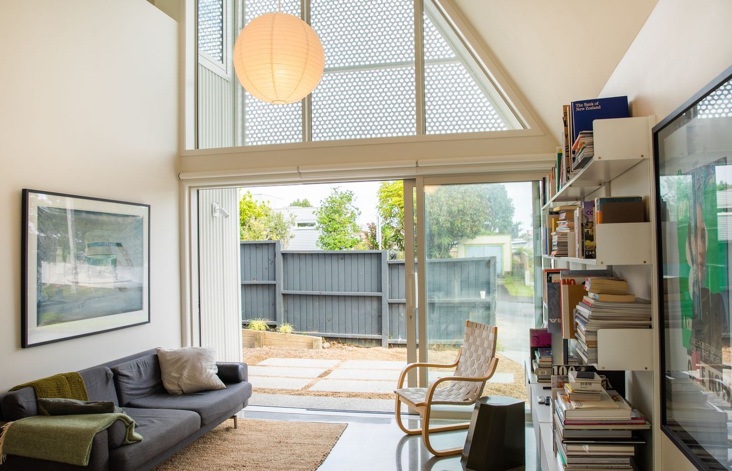 The perforated screen on the triangular window allows filtered light in and casts a pattern on the white walls.