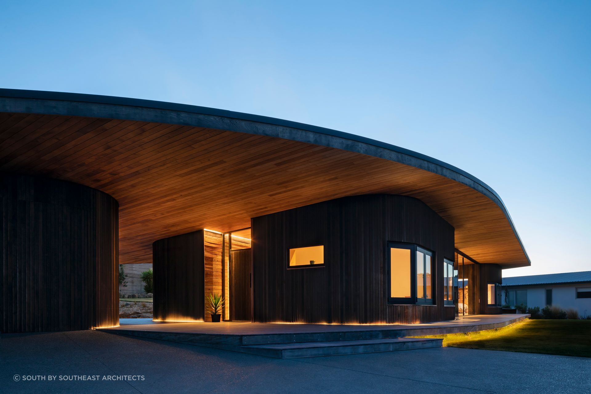 A deck wraps right around the curved exterior of this beautiful home - Photography: Sarah Rowlands