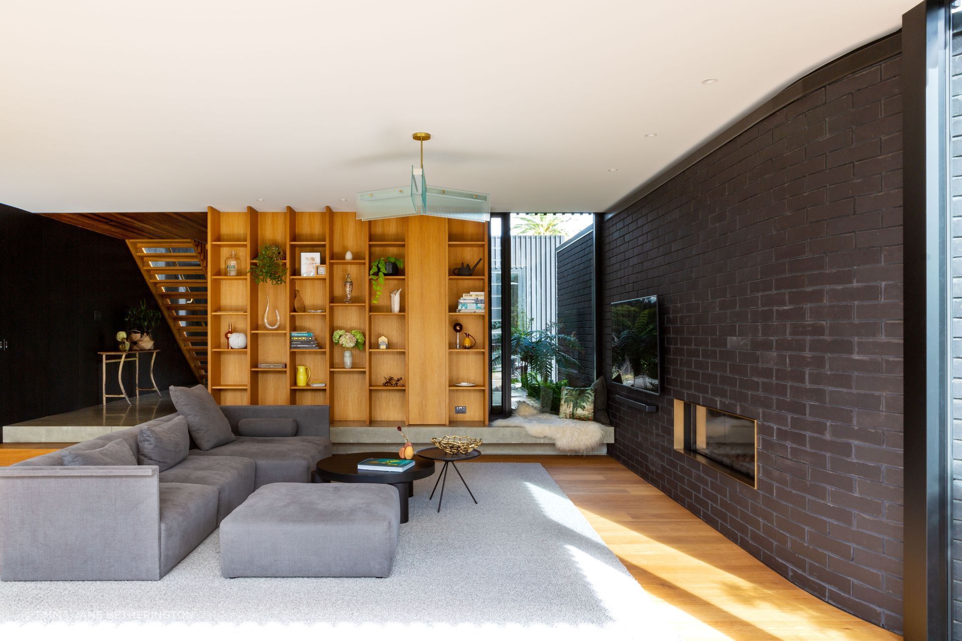The concrete floor of the foyer steps down into the living room, to increase the room height, and the negative detail underneath has LED lighting. The cosy corner looks out to the entry courtyard. “With underfloor heating, it's slightly warm,” says Rina.