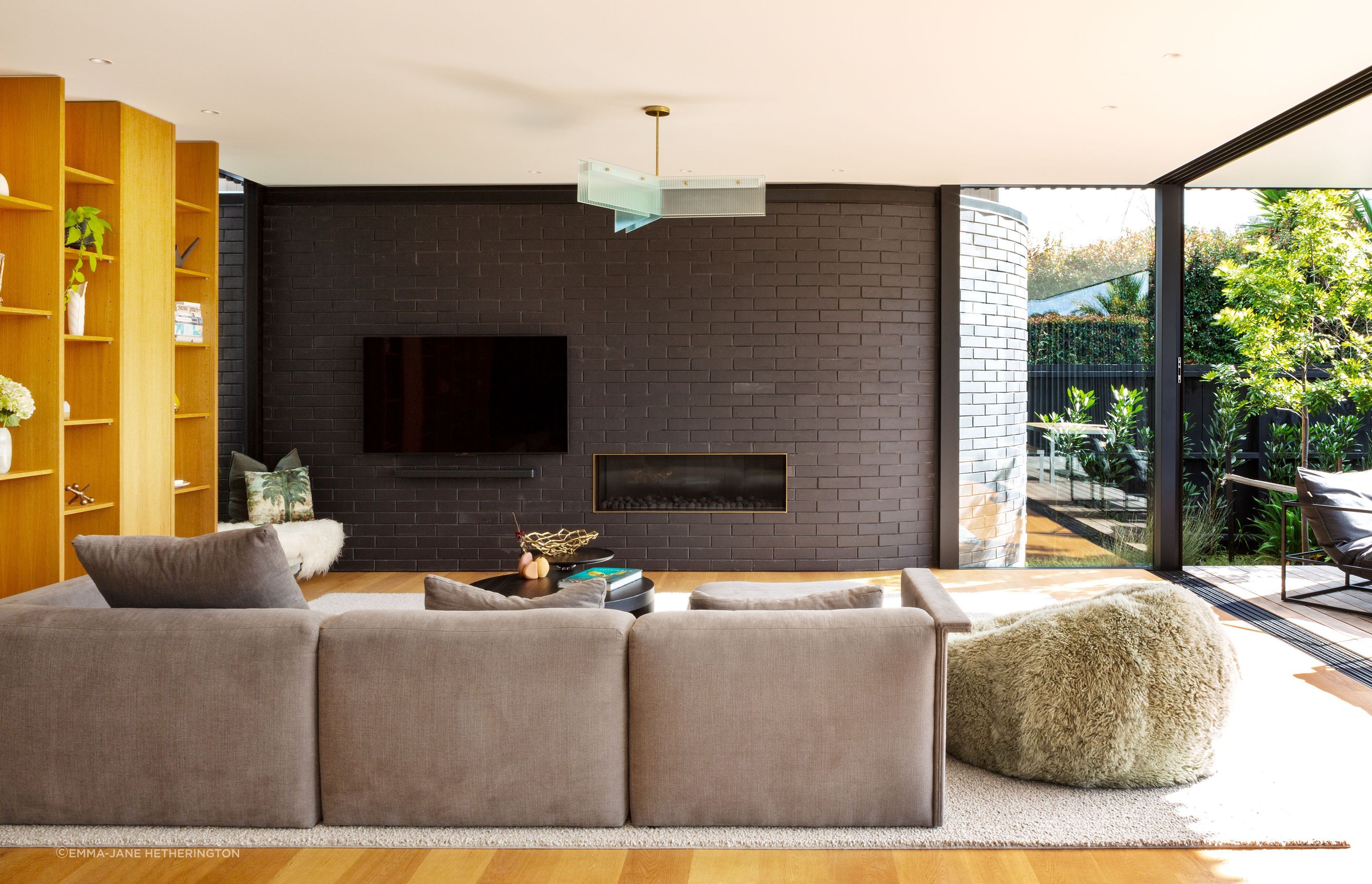 “This is the side wall of the house almost peeling out. It’s like kinetic movement: the idea that the house has opened itself up to the view,” says Tim. The insert around the Escea fireplace was made by Powersurge. The couch is from Simon James.