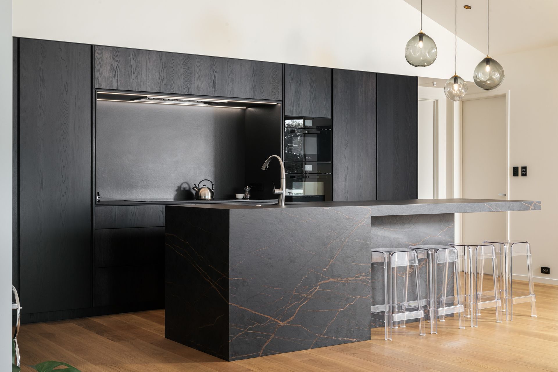 The kitchen features dark stone and black cabinetry – a contrast to the rest of the space.