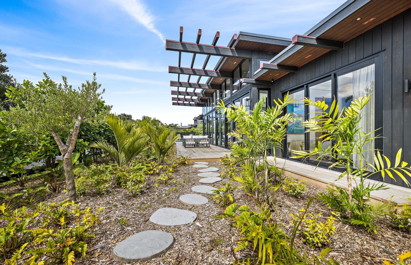 Designed by Hulena Architects, the Omaha home was constructed by Bridgens Construction and Design. It offers plenty of indoor-outdoor flow, ideal for the coastal environment. Stained in Resene Crowshead, the cedar is the perfect backdrop for the surrounding plants.
