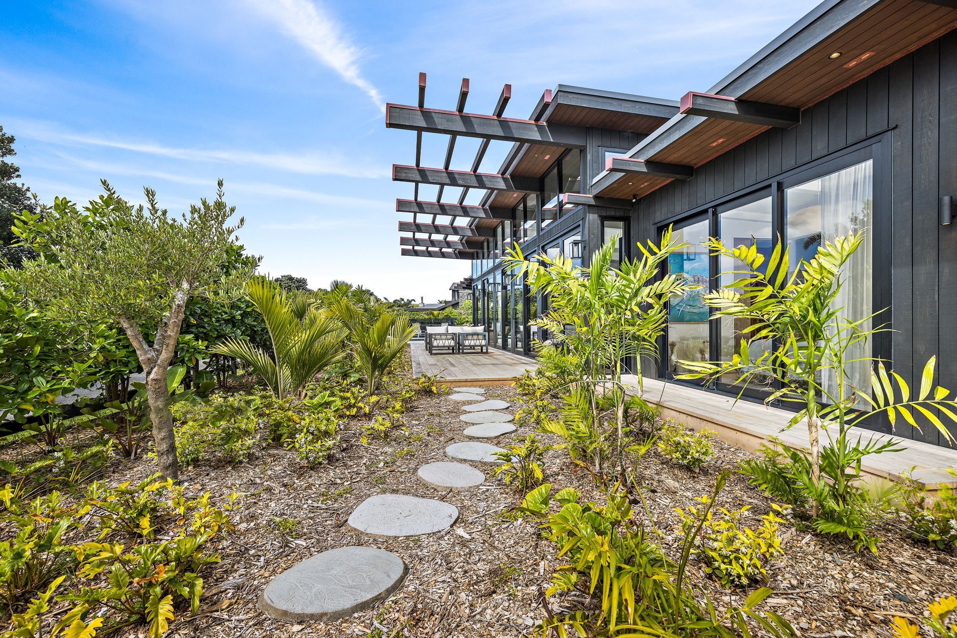 Designed by Hulena Architects, the Omaha home was constructed by Bridgens Construction and Design. It offers plenty of indoor-outdoor flow, ideal for the coastal environment. Stained in Resene Crowshead, the cedar is the perfect backdrop for the surrounding plants.