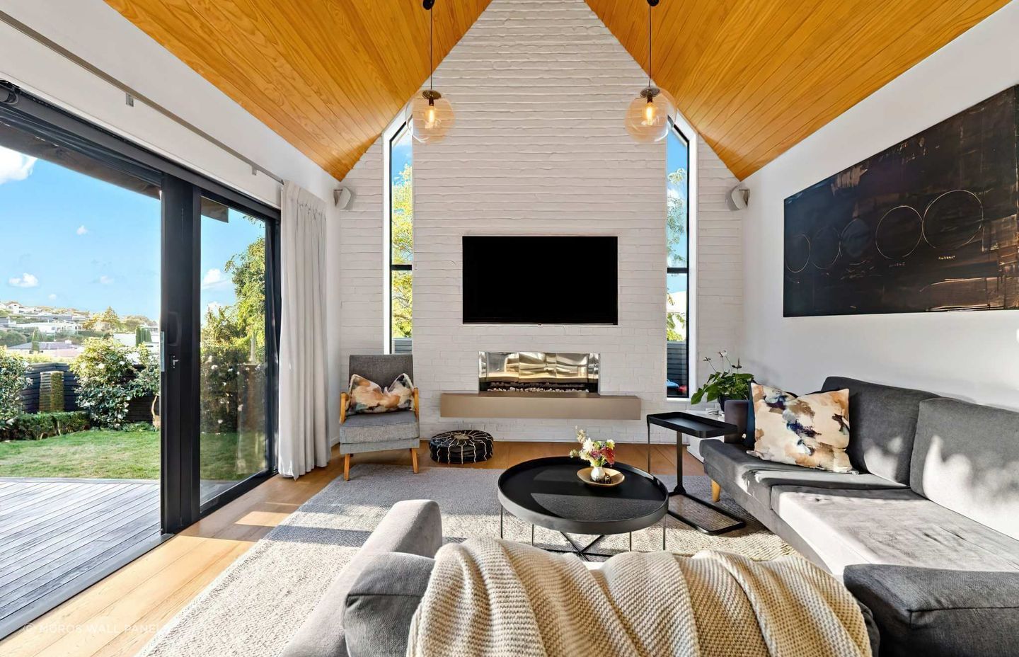 In this home, a feature wall was added to the living room in Muros White Loft Brick panels, painted in a custom Resene colour similar to Resene Half Rice Cake. Design by Blackbird Projects.
