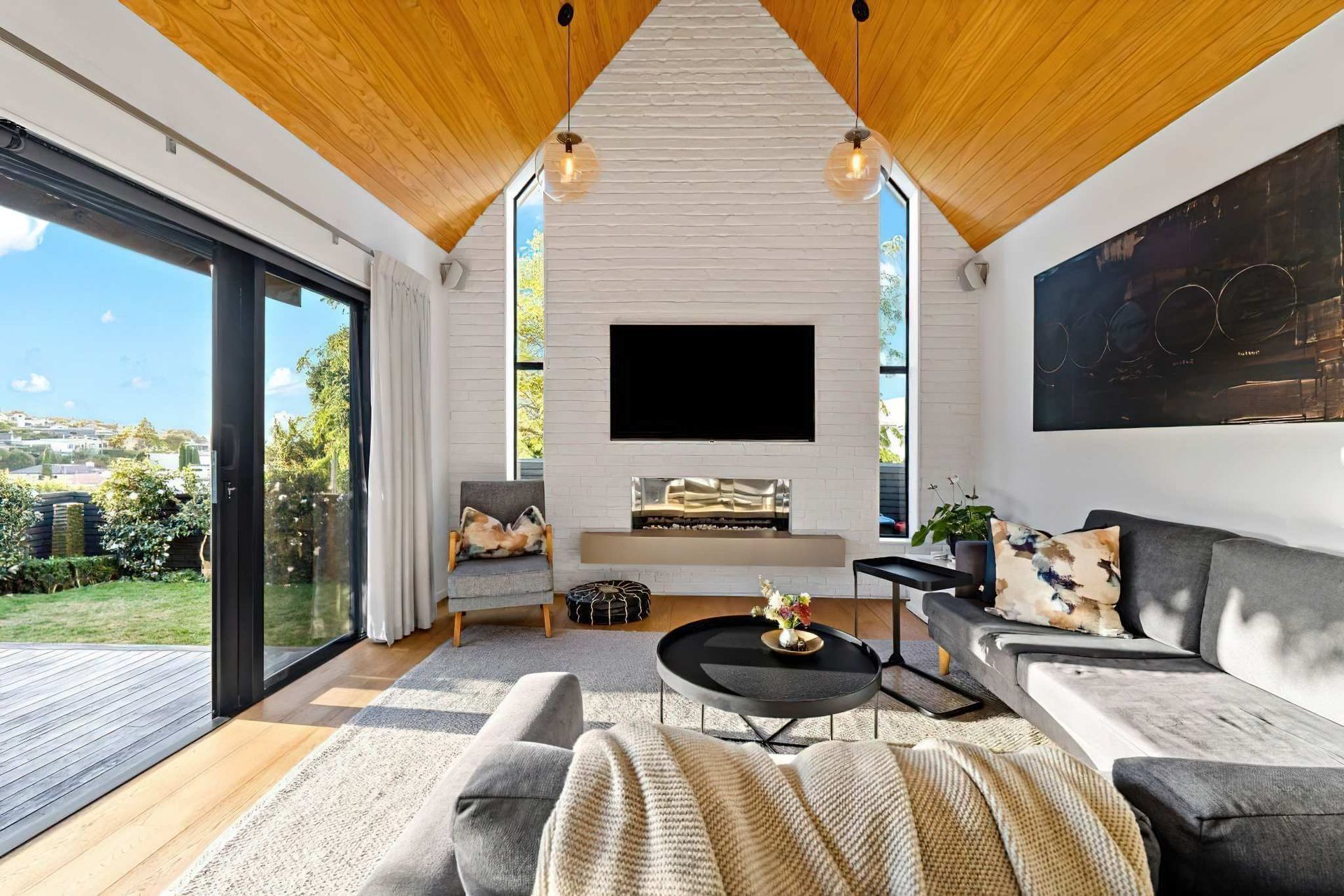 In this home, a feature wall was added to the living room in Muros White Loft Brick panels, painted in a custom Resene colour similar to Resene Half Rice Cake. Design by Blackbird Projects.