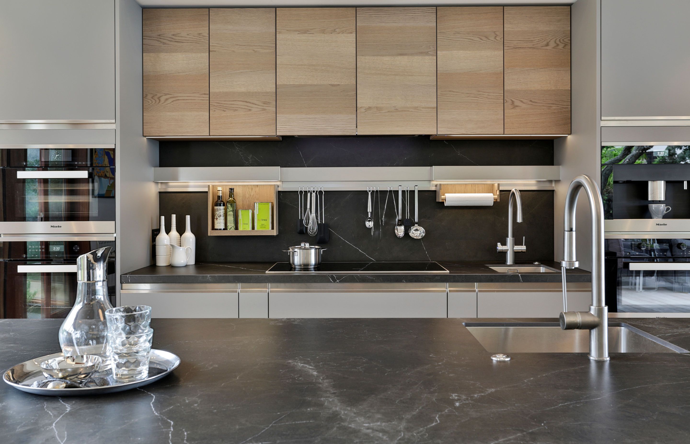 Fossil oak wood veneer was chosen for the upper cabinets providing textural contrast to the Armour Grigio finish of the other cabinetry. The iStone porcelain splashback, bench top and island provide dramatic contrast while the innovative Mensolinea shelf 