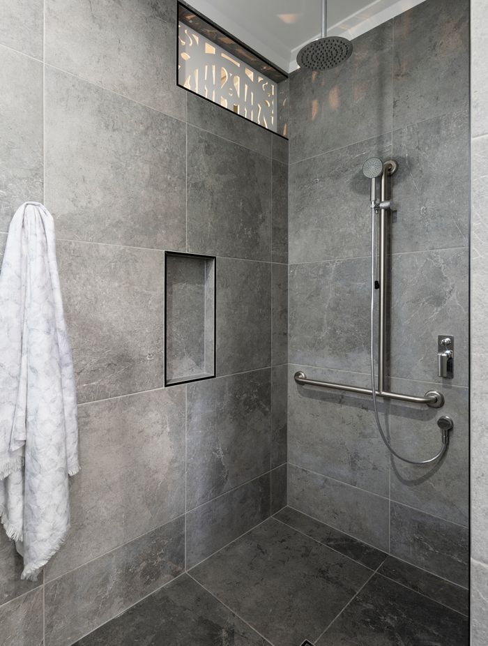 A grab bar and detatchable shower head make bathing more accessible | Auntie's Hut by 4305 Design | Photography by Angus Martin