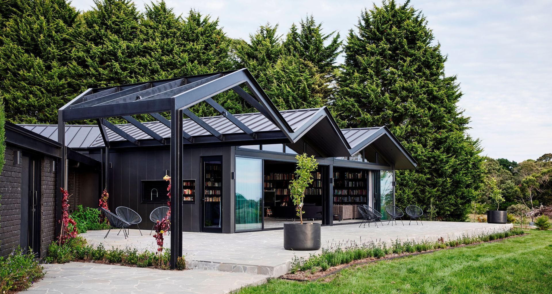 The brick exterior of this 1980s-era home and bold steel pergola have been seamlessly integrated thanks to a monochromatic refurbishment featuring Resene Lumbersider Low Sheen CoolColour in Bokara Grey on the bricks and Lumbersider Low Sheen CoolColour Black on the pergola. 
Project: Atlas Architects. Image: Tess Kelly.