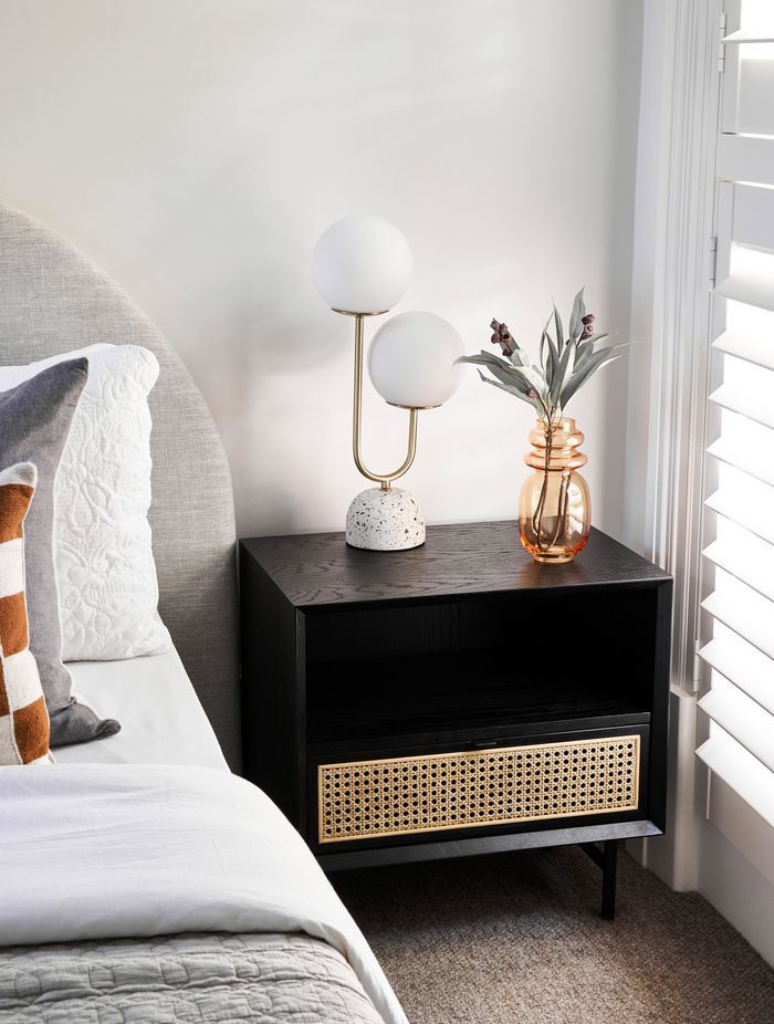 Bedside tables made of a mixture of materials, such as this one made of stained timber and rattan, incorporate different styles in their design. Featured product: Betty Side Table.