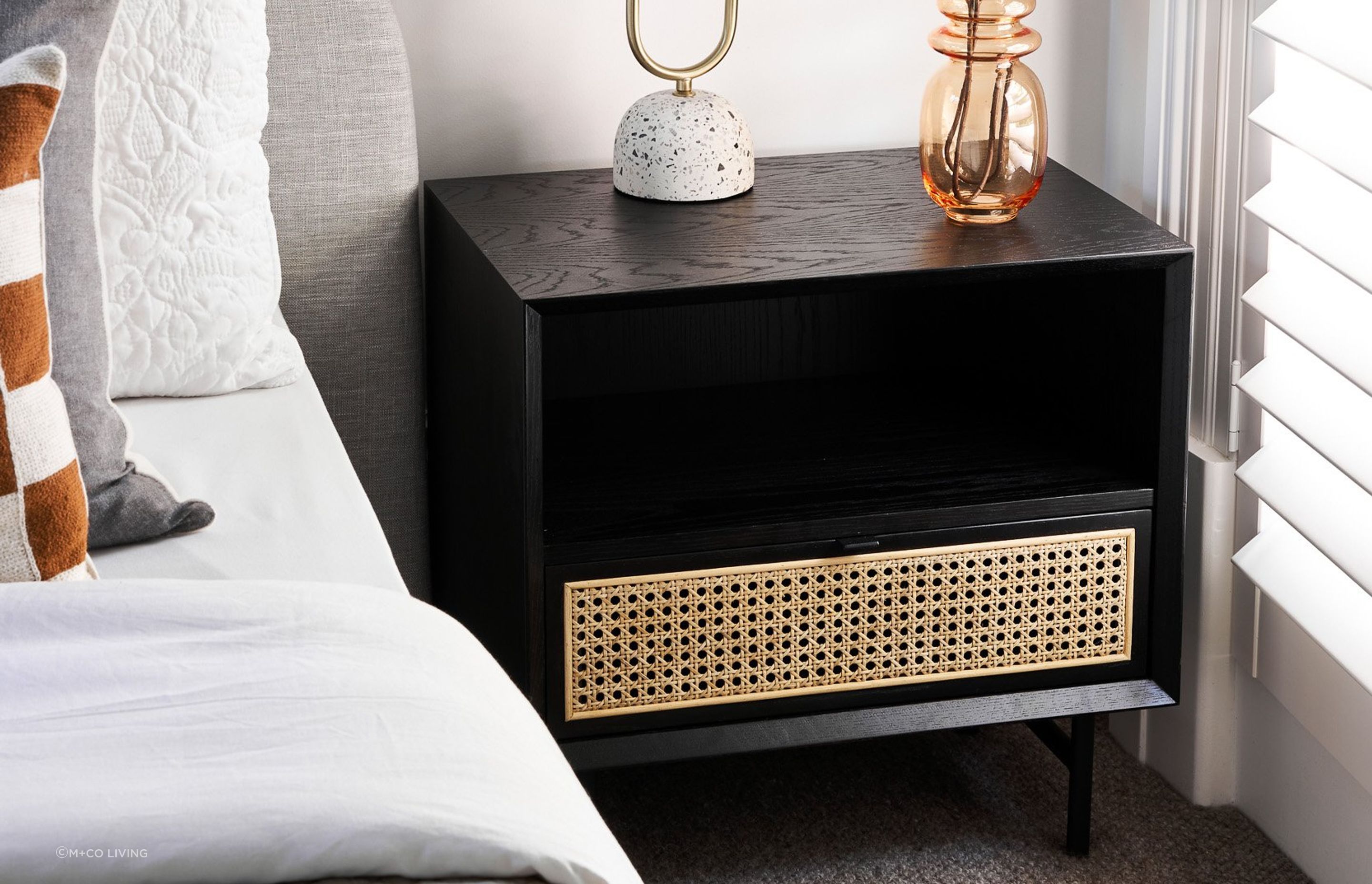 Bedside tables made of a mixture of materials, such as this one made of stained timber and rattan, incorporate different styles in their design. Featured product: Betty Side Table.