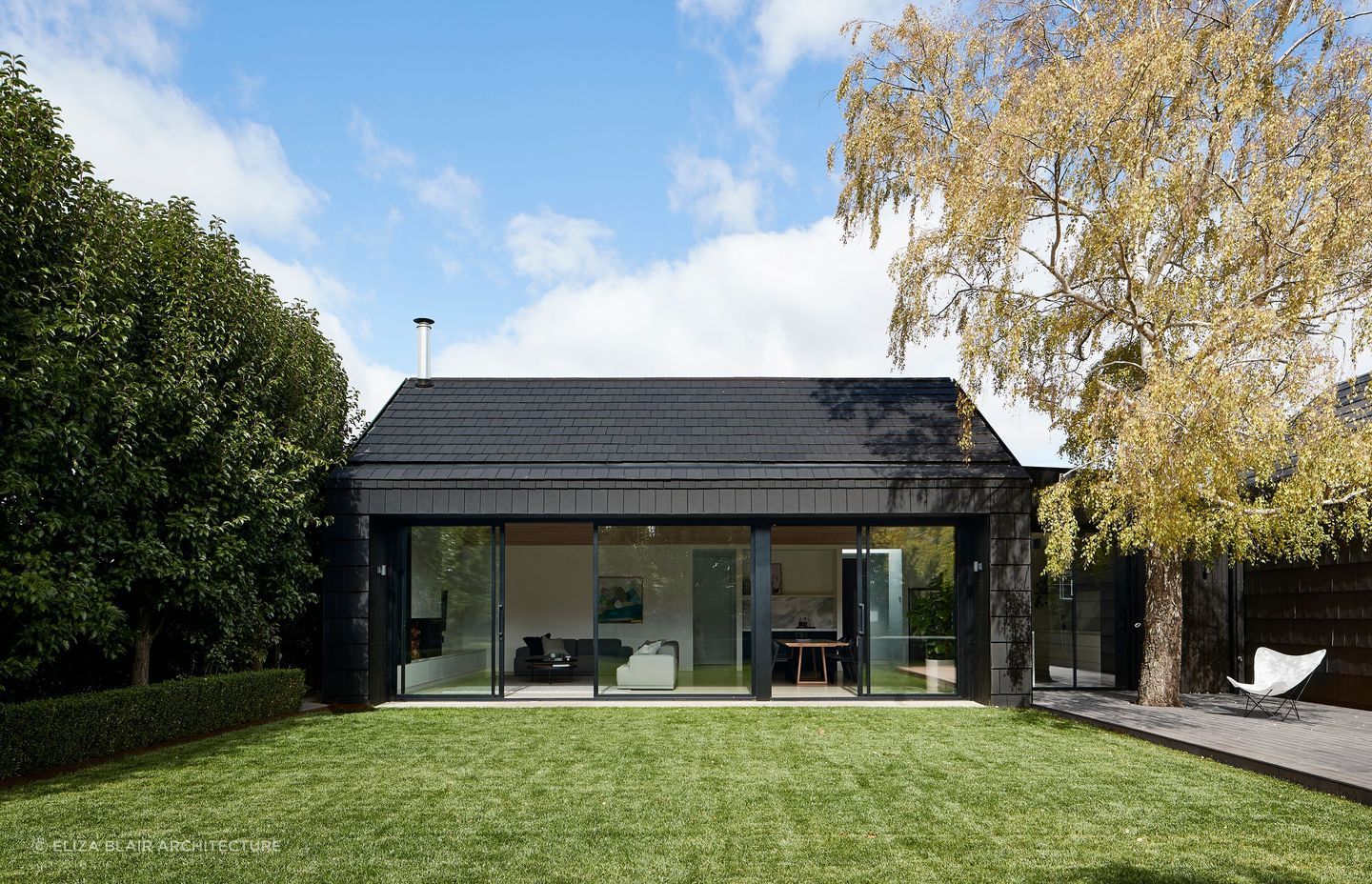The dark exterior provides a striking contrast with the outdoor greenery. Photographer: Shannon McGrath.