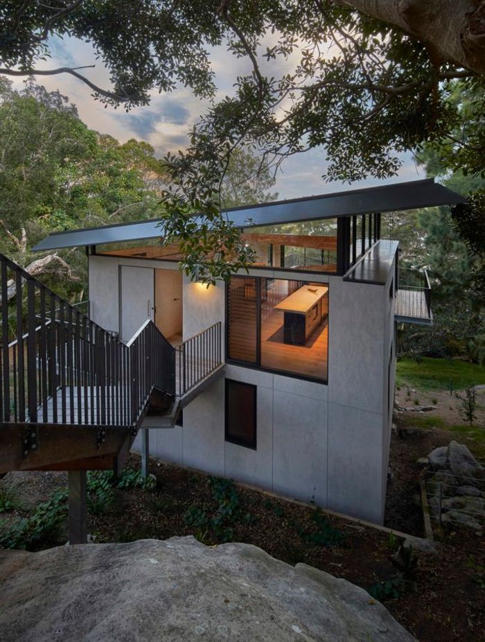 The house tucked below the rock shelf with view through the highlight windows