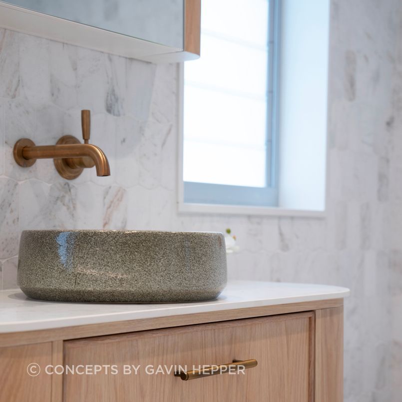 A handmade clay basin by Robert Gordon is paired with bronze tapware and natural stone for an elevated bathroom space