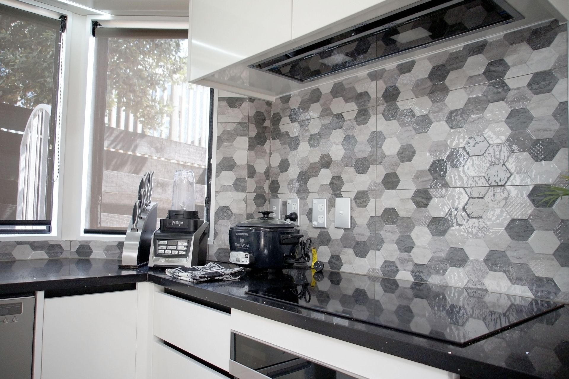 Kitchen renovation in Bucklands Beach: Hexagon shaped black and grey textured tiles were added as a backplash to add interest, drama and texture to the kitchen.