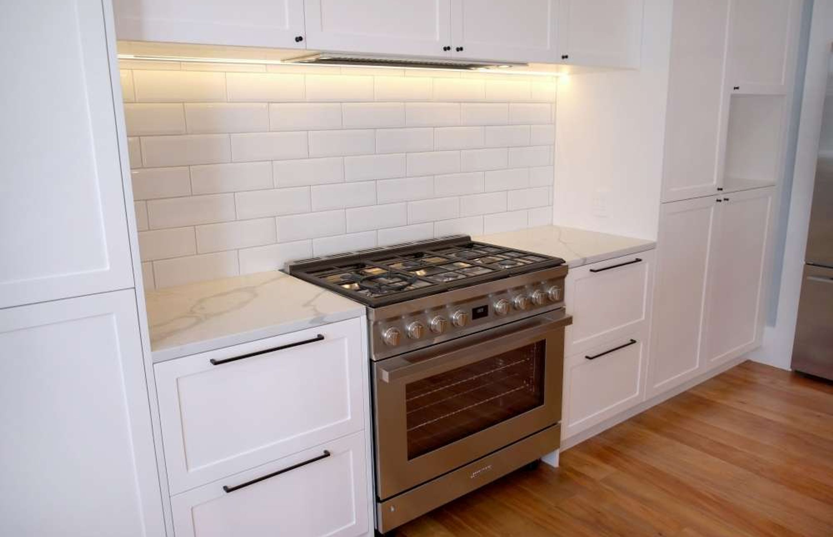 A grey cooking range was used with white subway tiles as a backsplash for a timeless classic design – Kitchen renovation in Epsom
