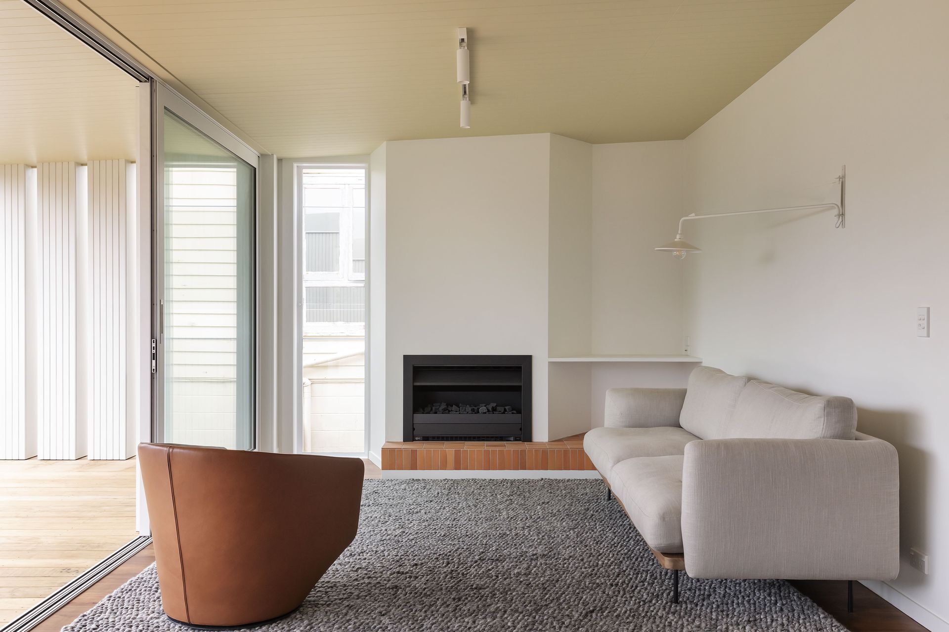 A geometric wall and brick hearth add visual interest to the lounge. Photo: David Straight