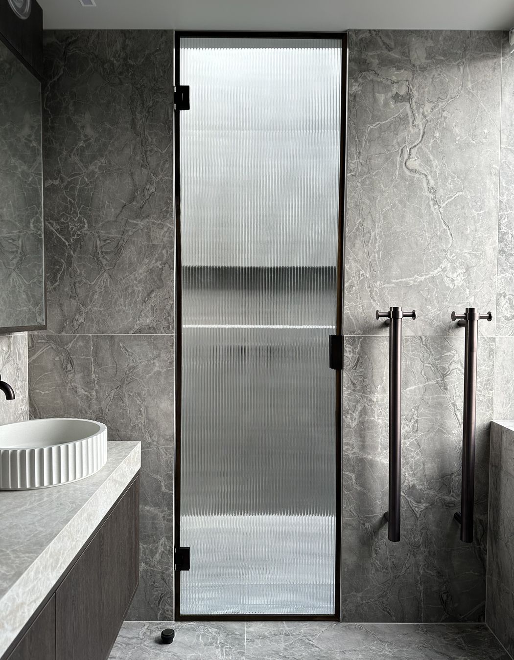 The reeded glass shower door is a beautiful, modern touch in this bathroom.