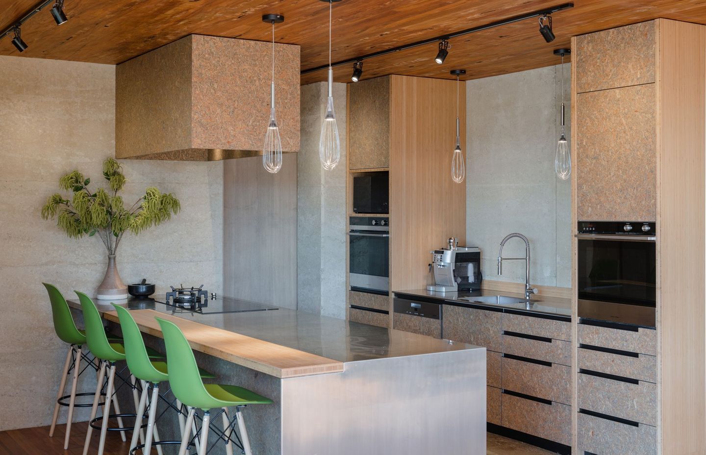 Strand board, a material not usually associated with residential architecture, was chosen for the kitchen cabinetry and imparts a strong textural aesthetic that contrasts nicely with the rammed earth walls.
