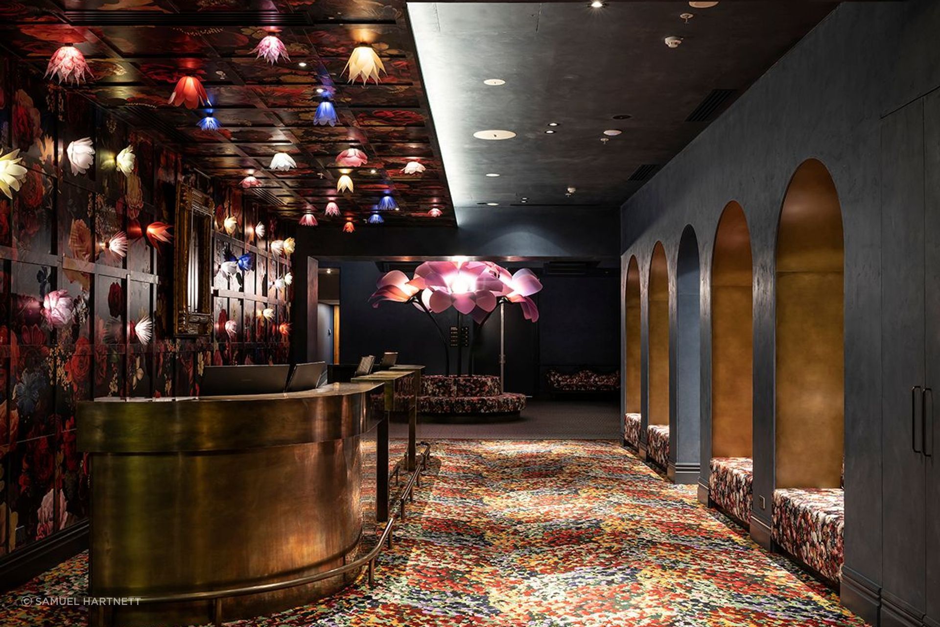 “There were already arches in all the doorways in the building, so we replicated them throughout to tie that through,” says Material Creative’s Toni Brandso. The flower lights and the oversize sculpture were created by Angus Muir Design.
