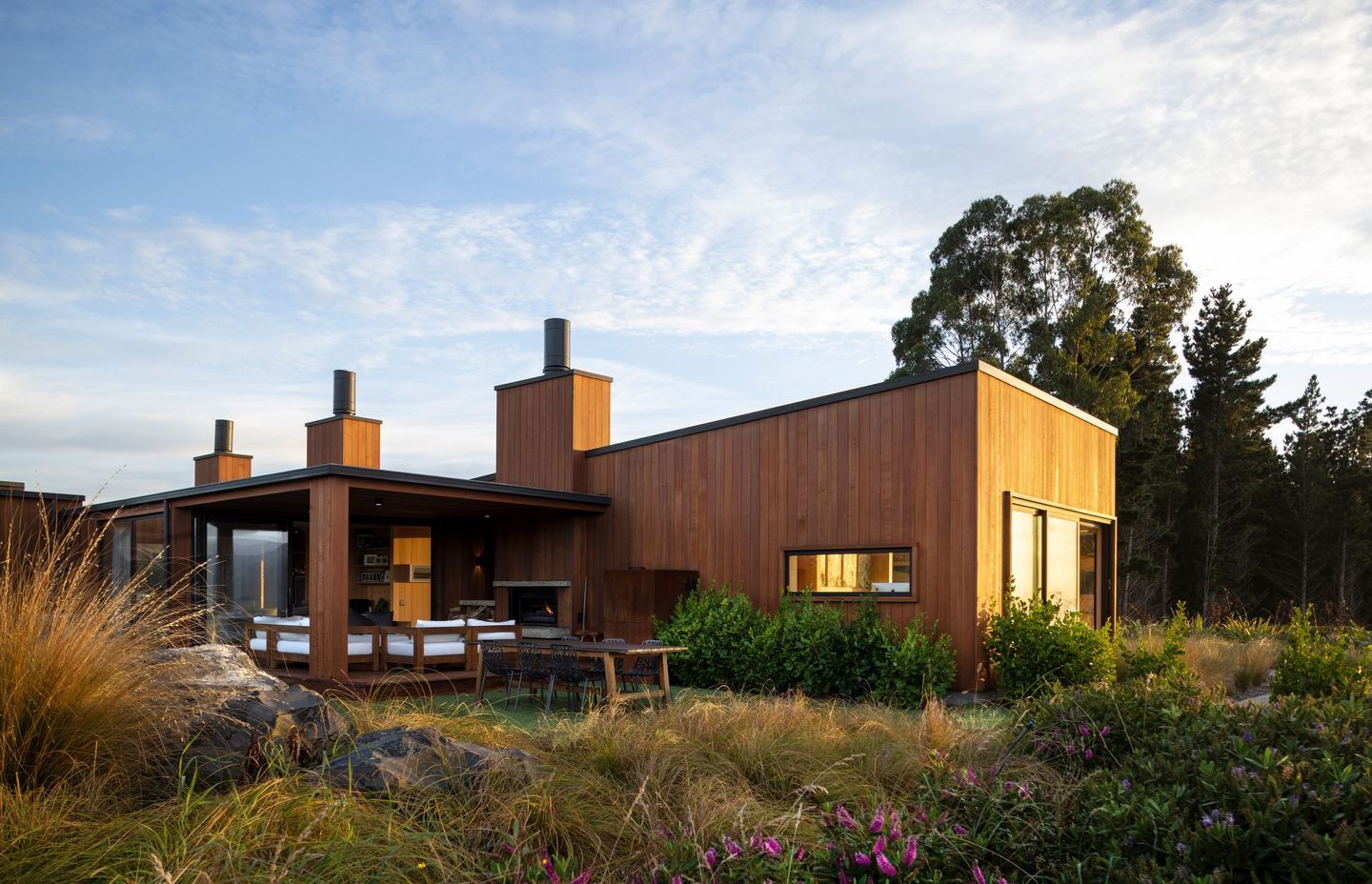 The west-facing side of Coastal Retreat, designed with an outdoor living area that captures the sunset over Blueskin Bay. | Photographer: Graham Warman