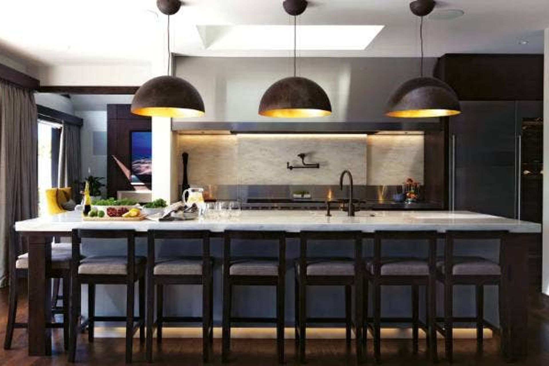 Entertaining was at the heart of the McNalls' plans for rebuilding their West Harbour home, so behind the main kitchen is a scullery with a commercial oven and dishwasher; the Corian benchtop is a soft contrast to the stainless steel and the light shades are from Lighthouse; the bar stools were custom-made by Modern Chair in Mt Roskill.