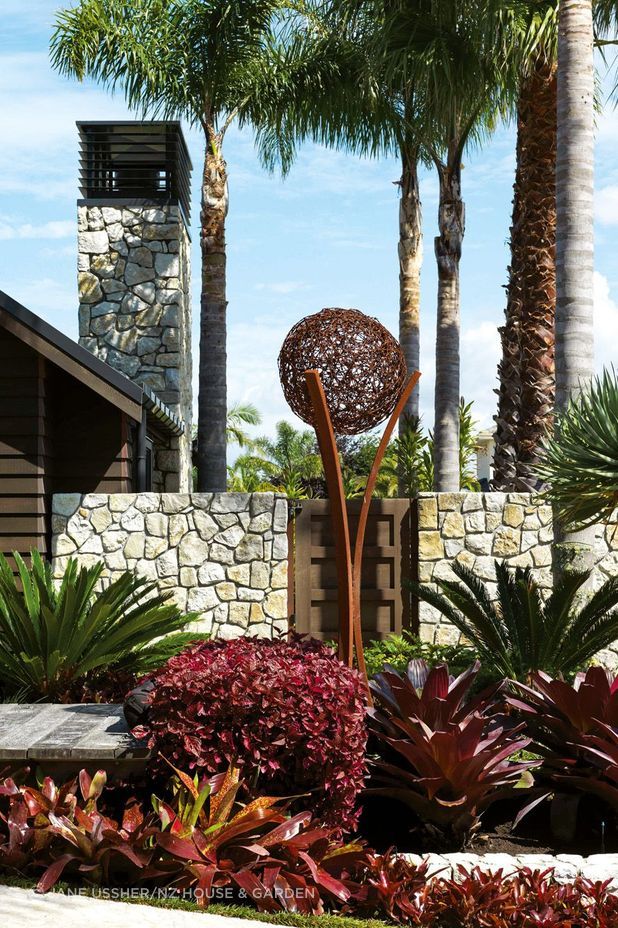 A boardwalk adds to the resort-like feel of the entrance, with planting that includes cycads, iresine and bromeliads; the sculpture is by Wire Art – the couple spotted a similar one at a Wānaka vineyard.