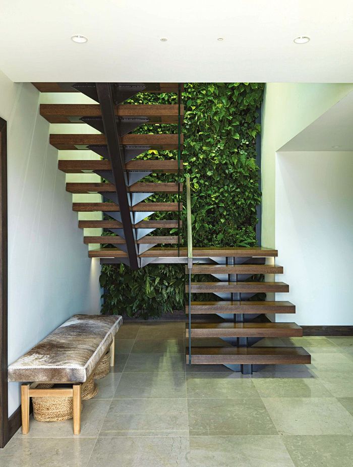 The floating stairs give an airy feel to the stairwell; the McNalls have chosen earthy, natural materials like the cowhide-covered bench and the ivory cross-cut limestone tiles used inside and out.