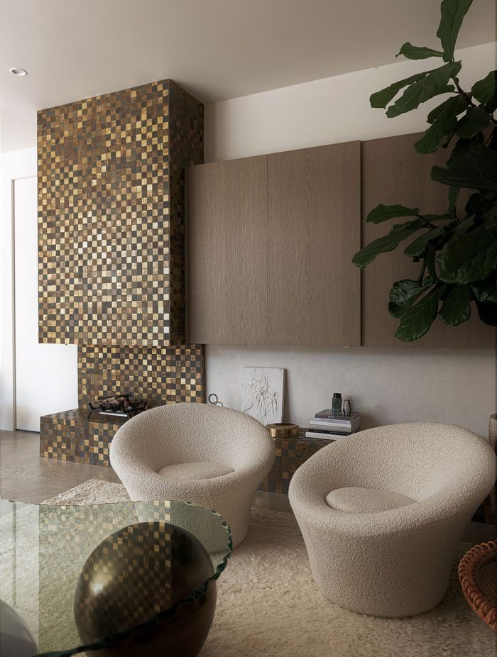 Tiny brass tiles were used to create this glittering façade for the fireplace, hearth, and chimney.