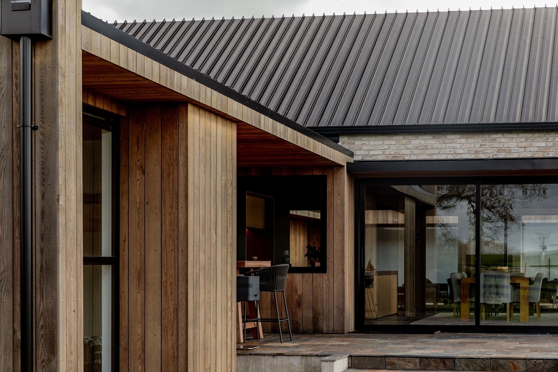 On either side of the living room gable building are sheltered stone courtyards, flanked with brick and cedar-clad walls.