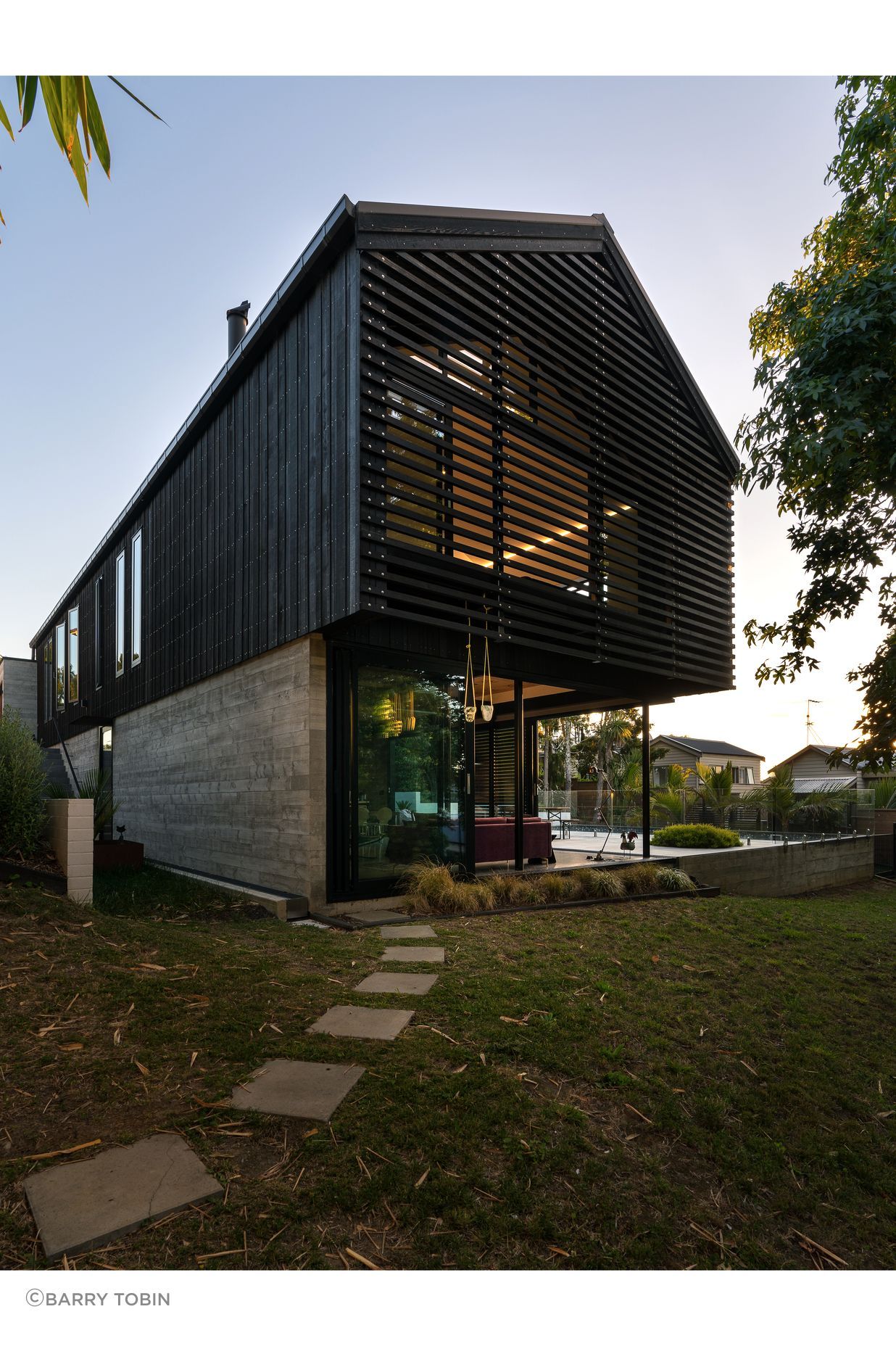 The family home of architect Clive Chapman of Pacific Environments Architects in Auckland. The gable roof, the vertical siding, the small windows and the strength of the concrete and corten steel are all references to the industrial shed feel that Clive wanted.