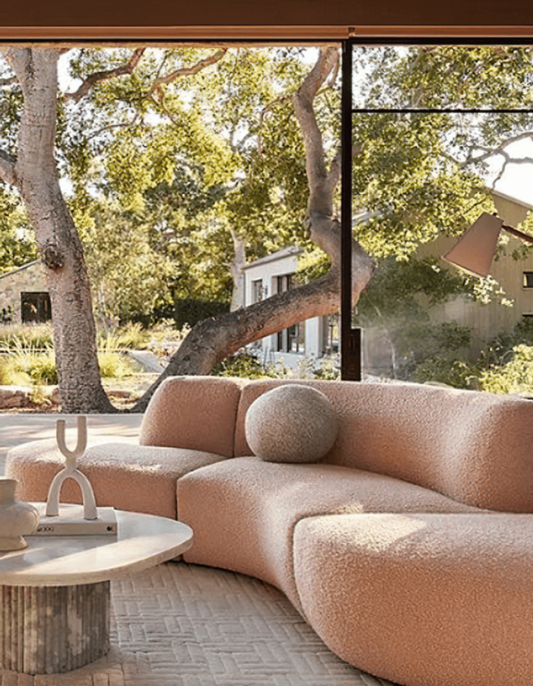 Image Credit:  Anthropologie | Curved Sofa in clay tones + biophilic design