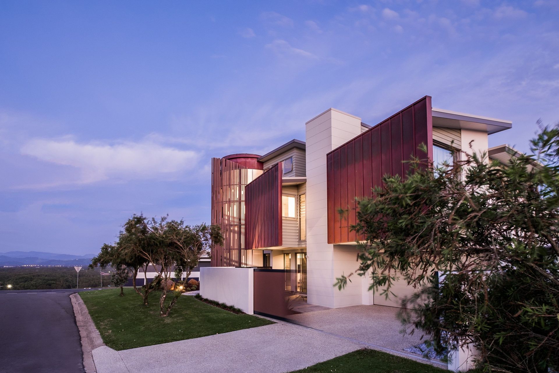 As dusk falls, the home's weathered metal panels, stands out against the gentle evening sky.