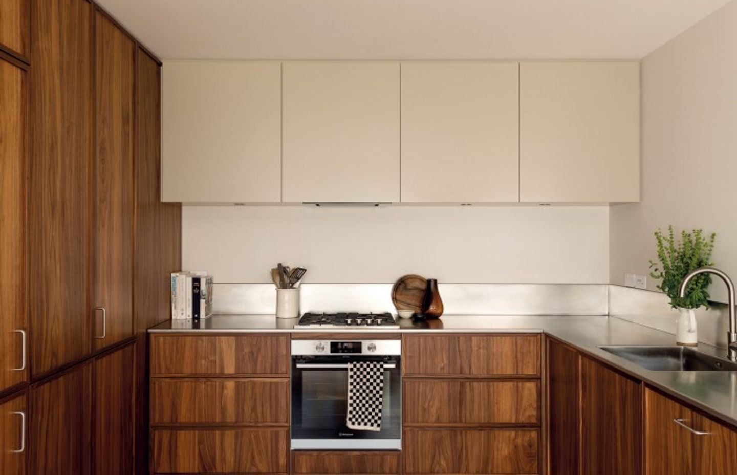 KITCHEN Floor-to-ceiling walnut-veneer cabinetry replaced a window in this generous but well-used space. “I always wanted stainless steel,” says Bailey about the utilitarian benchtop and splashback. “We were set on a minimal look and didn’t want a join in the benchtop, so that was a challenge when it came to bringing in the L-shaped piece. Seven guys attempted to place it, but ended up having to cut some of the wall to get it in without disturbing the cabinetry!” Bailey kept the handles here to a minimum as well, using D Pulls by Häfele only where strictly necessary. The appliances are by Fisher and Paykel and Westinghouse, and the Elysian mixer is from ABI Interiors.