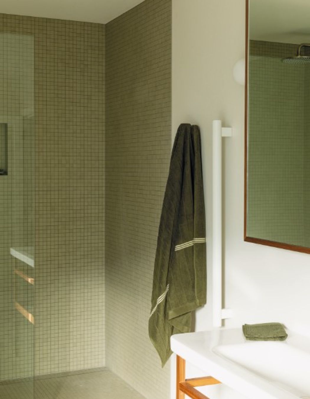 BATHROOM Here, a leggy DuraStyle vanity by Durafit is teamed with Milani tapware from ABI Interiors. The ceramic wall and floor tiles from Artedomus have a matte finish that Bailey sought to sync with the look of the Oasis freestanding bath by Concrete Nation, and the walls are in Porter’s Paints Cashmere to match the other main rooms in the house. On the vanity and Grab 90 rails by Avenir from Plumbline are organic cotton towels by Bailey’s own luxury brand, Baina. Pictured right, a large, frosted-glass window opens like a door to provide maximum ventilation in this space. “In the morning, the sun streams in through it — it’s beautiful,” says Bailey.