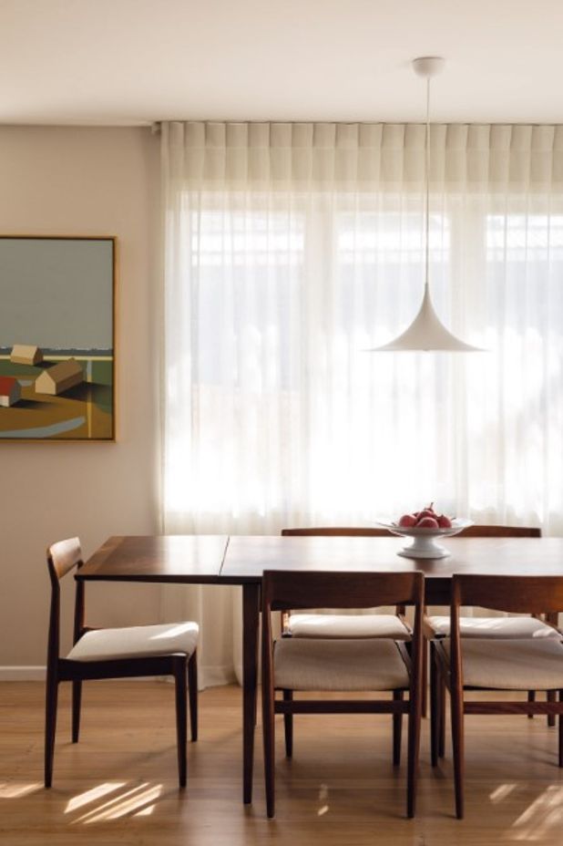 Linen curtains on a curved track provide privacy from the neighbours beside Shores II by Bohdan Burenko on the adjacent wall. The dining table and chairs below the Semi pendant by Gubi were sourced from Mr Bigglesworthy.