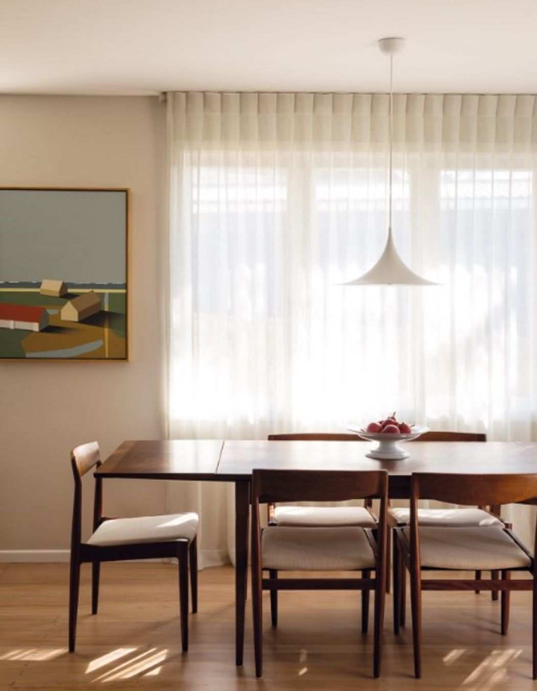 Linen curtains on a curved track provide privacy from the neighbours beside Shores II by Bohdan Burenko on the adjacent wall. The dining table and chairs below the Semi pendant by Gubi were sourced from Mr Bigglesworthy.