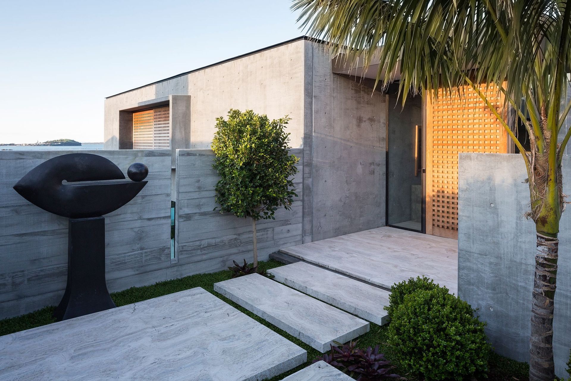 Contrasting textures between the precast concrete cladding and the timber door add depth and dimension to this immaculate home in Hobson Bay