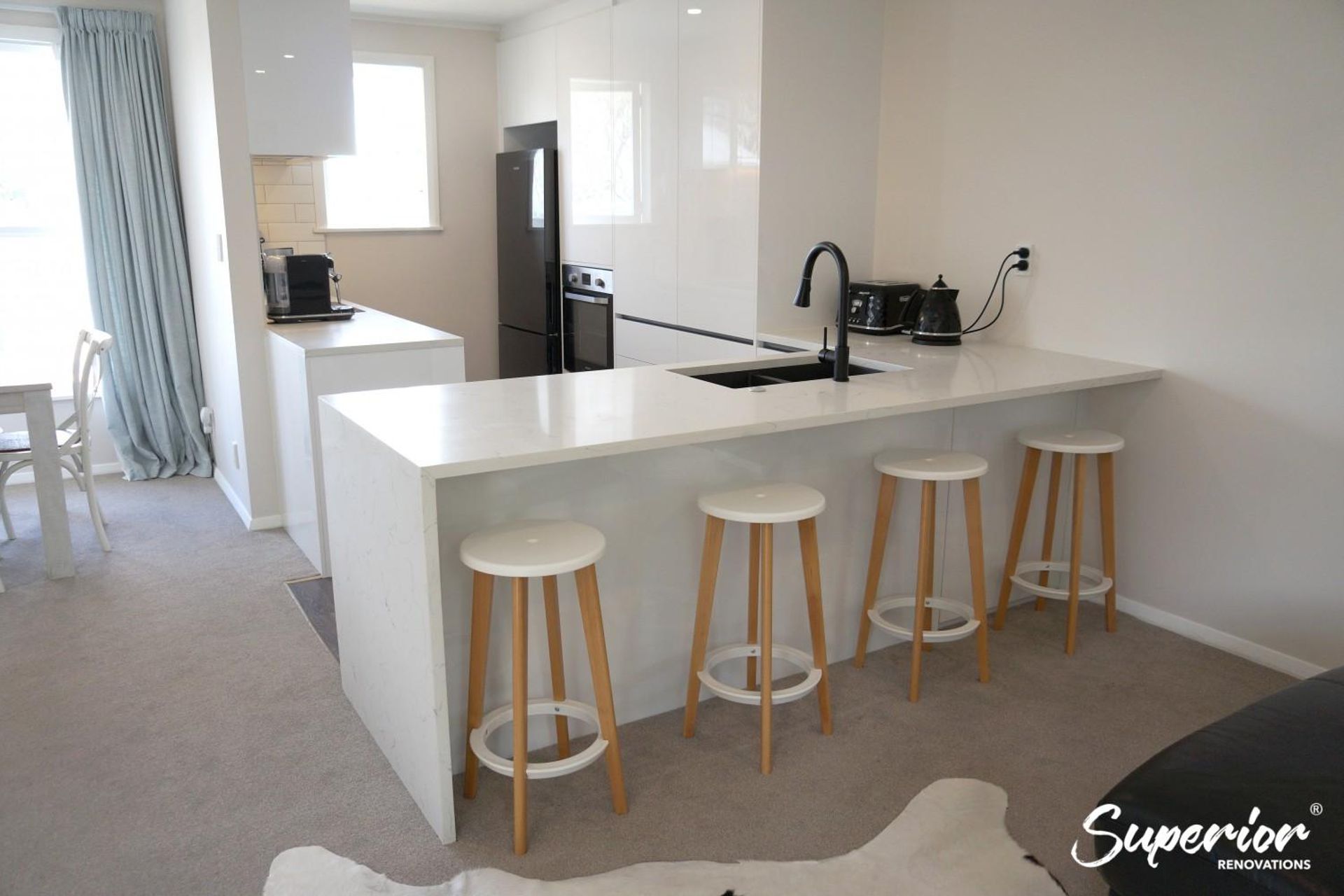 Kitchen renovation in Greenlane – The island doubles as a dining area, has a sink and counter space for prep and storage on the other side in form of cabinets